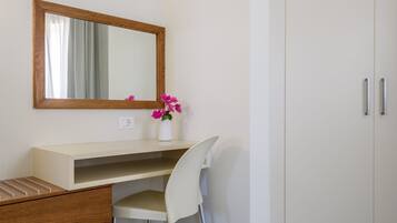 A modern bathroom with a wooden-framed mirror, a white sink, a white chair, and a cabinet with drawers.