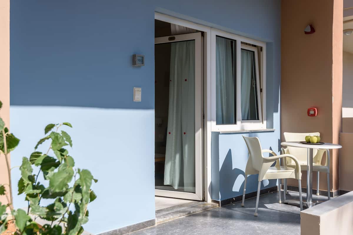 A balcony with a sliding glass door, a small table with chairs, and a potted plant.