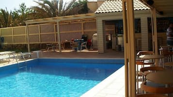 Una piscina al aire libre de temporada, sombrillas