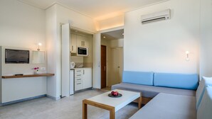 A modern living room with a sofa, a coffee table, a TV, and a kitchen area.