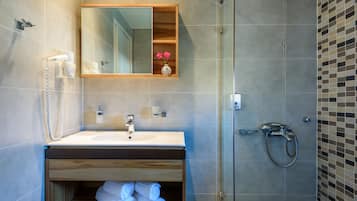 A modern bathroom with a sink, mirror, and shower.