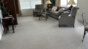 Una sala de estar con sofá, sillones, una mesita de centro, lámpara y ventilador de techo.