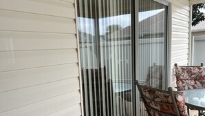 Un patio cubierto con puerta corrediza de vidrio, una mesa con sillas y un enchufe en la pared.