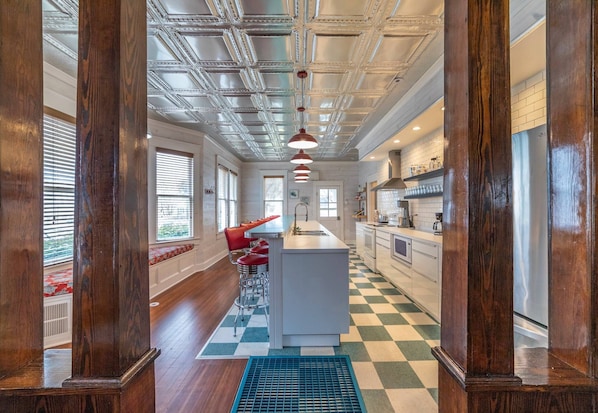 A modern kitchen with wooden beams, a central island, and a checkered floor.