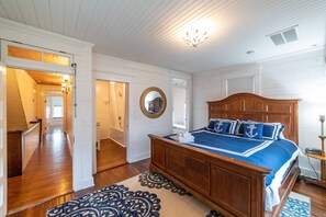 Un dormitorio con cama de madera, un espejo redondo y una escalera que conduce a otra habitación.