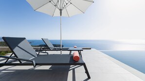 Una terraza con dos sillones, una mesa y un gran sombrilla.