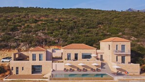 Un moderno complejo turístico con edificios de piedra, piscina y un telón de fondo montañoso.