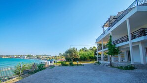 A coastal hotel with a paved driveway, a fenced garden, and a view of the sea.