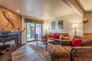 Cozy living room with a fireplace, comfortable seating, and a view to an outdoor area.