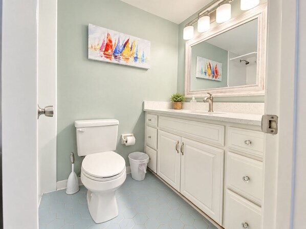 A bathroom with a toilet, sink, and cabinet, featuring a light green wall and hexagonal tile flooring. - Point Matanzas - Intracoastal Water-Front, Amazing Views, Daytime Dock, Pool (St. Augustine)
