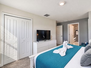 A hotel room with a bed, a television, a wardrobe, and a bathroom visible through an open door.
