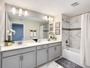 A modern bathroom with a double sink vanity, a large mirror, and a shower area.