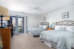 A bedroom with two beds, a ceiling fan, a lamp, a dresser, and a door leading to a balcony. - Fairway Villa 1304 at Rumbling Bald (Lake Lure)