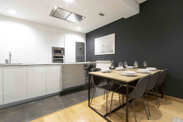 Een moderne keuken met witte kasten, een centraal eiland en een eethoek met een tafel gedekt voor vier personen.