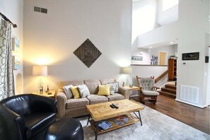 A living room with a sofa, a coffee table, a leather chair, a wooden side table, and a lamp.