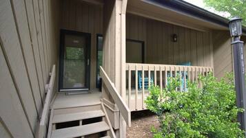 A wooden porch with a set of stairs leading to a door, a small window, and a mailbox.
