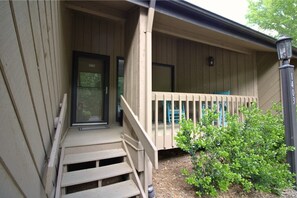 A wooden porch with a set of stairs leading to a door, a small window, and a mailbox. - Fairway Villa 1403 at Rumbling Bald (Lake Lure)