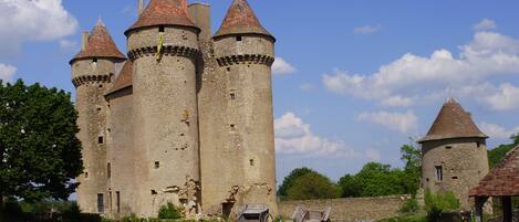 A historic castle with multiple towers and a cobblestone pathway leading to a carriage.