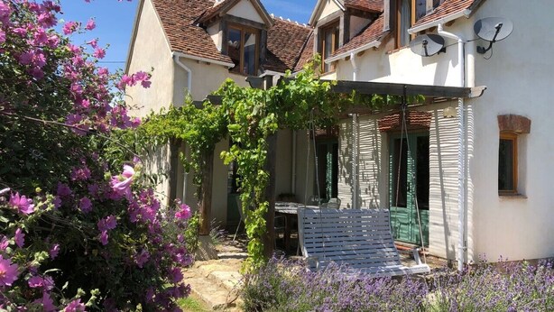 A house with a covered patio, a garden with flowering plants, and a stone pathway. - Berrichonne character house (St Jeanvrin)