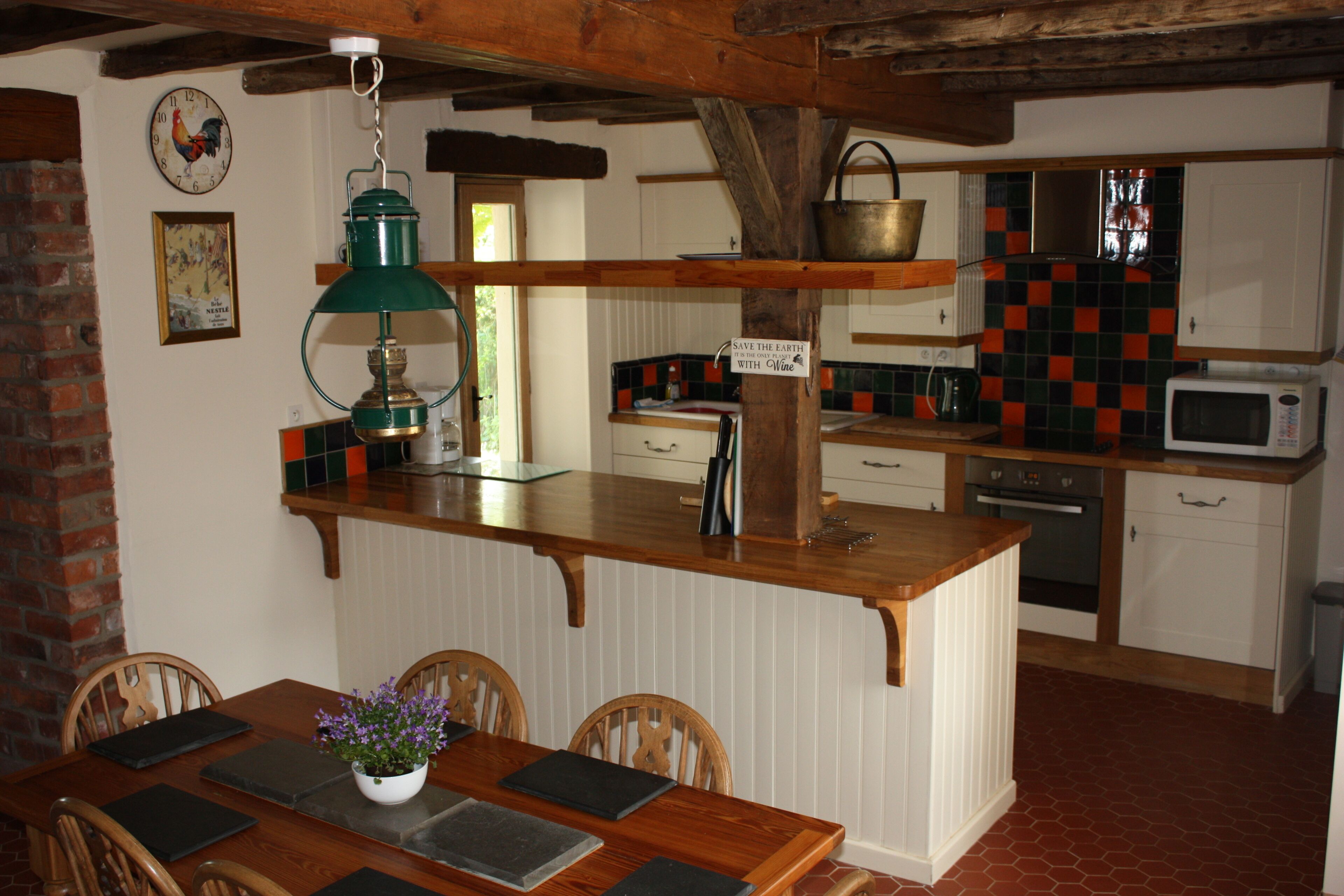 A kitchen with a wooden island, white cabinets, a microwave, and a hanging pot rack.