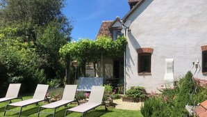 A garden with a white building, a bench, and a table. - Berrichonne character house (St Jeanvrin)