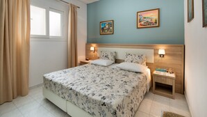 Une chambre à coucher comprenant un lit, deux tables de chevet, une fenêtre avec des rideaux et deux lampes fixées au mur.