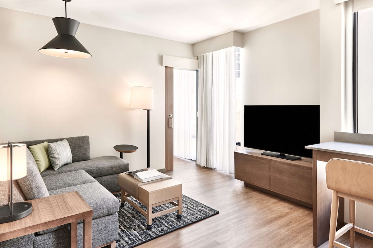 A modern living room with a sofa, a coffee table, a TV, and a desk.