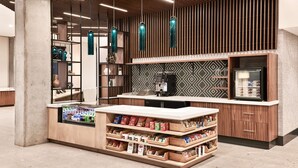 A modern kitchen area with a built-in coffee machine, a refrigerator, and a variety of snacks and beverages on open shelves. - Hyatt Place Phoenix / Downtown (Phoenix)