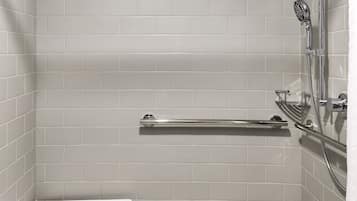 A shower with a handheld showerhead, a handheld shower seat, and a grab bar.