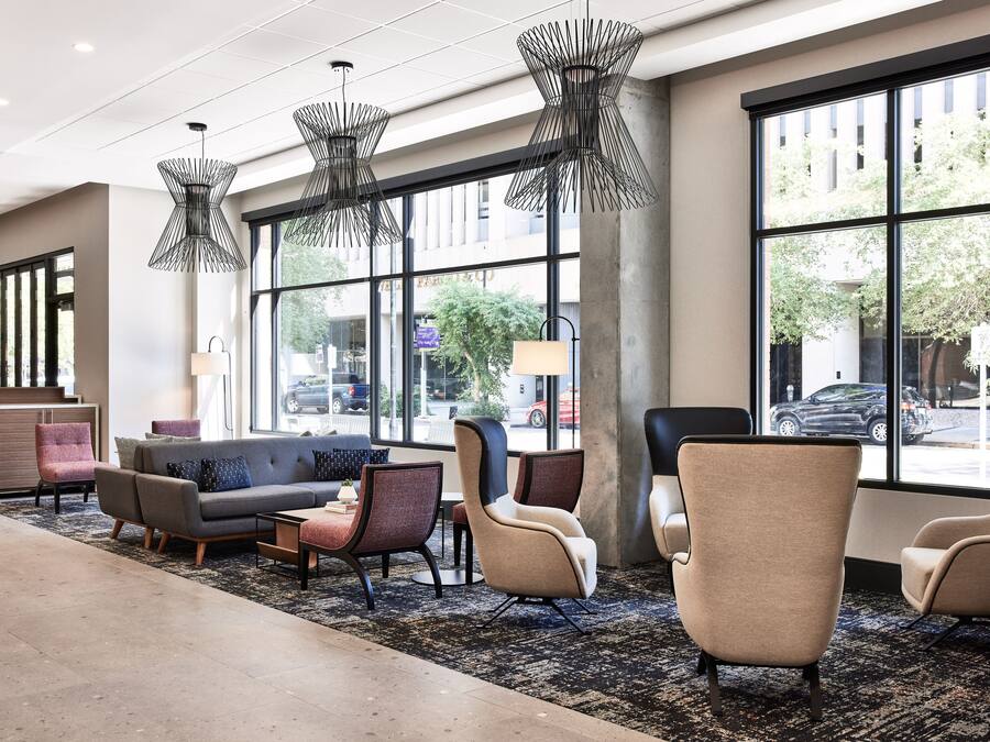 Eine moderne Lobby mit einer Couch, Sesseln und einem Couchtisch. Große Fenster bieten Blick auf die Straße.