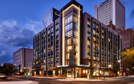 A multi-story hotel with a prominent corner entrance, large windows, and a well-lit facade.