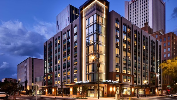 Un hôtel à plusieurs étages, doté d’une entrée d’angle remarquable, de grandes fenêtres et d’une façade bien éclairée.