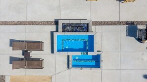 An aerial view of a pool area with two rectangular pools and a seating area with two chairs and a table.
