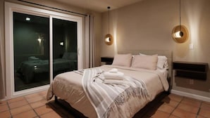 Een slaapkamer met een bed, een schuifdeur naar een balkon en twee hanglampen.