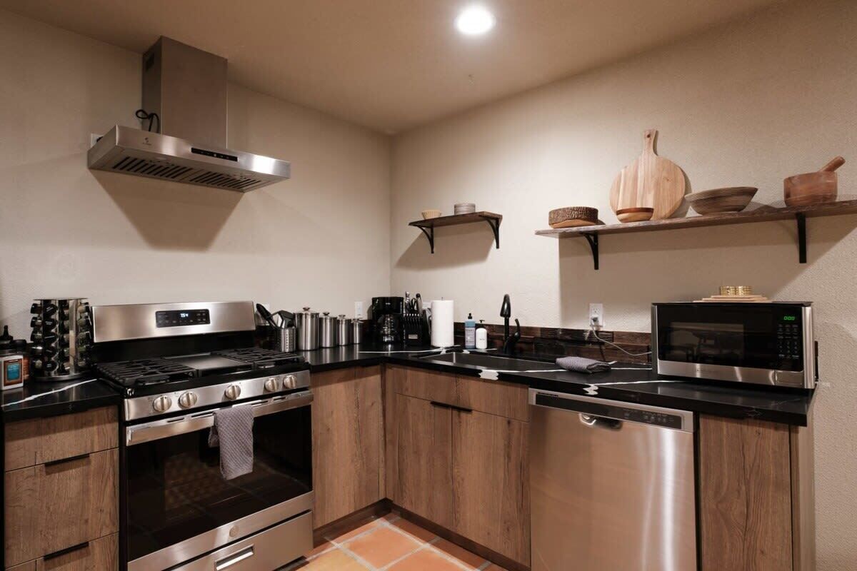 Una cocina moderna con electrodomésticos de acero inoxidable, armarios de madera y encimera negra.