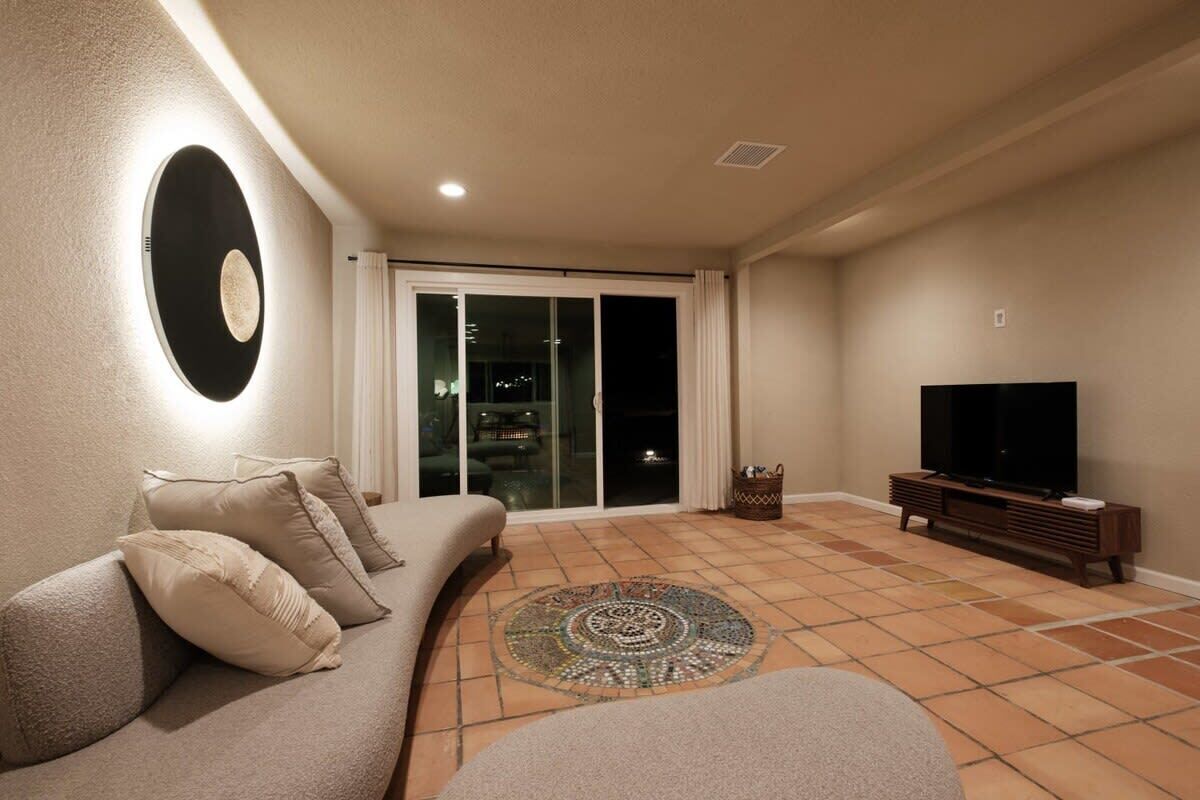 A living room with a sofa, a television, and a patterned rug.