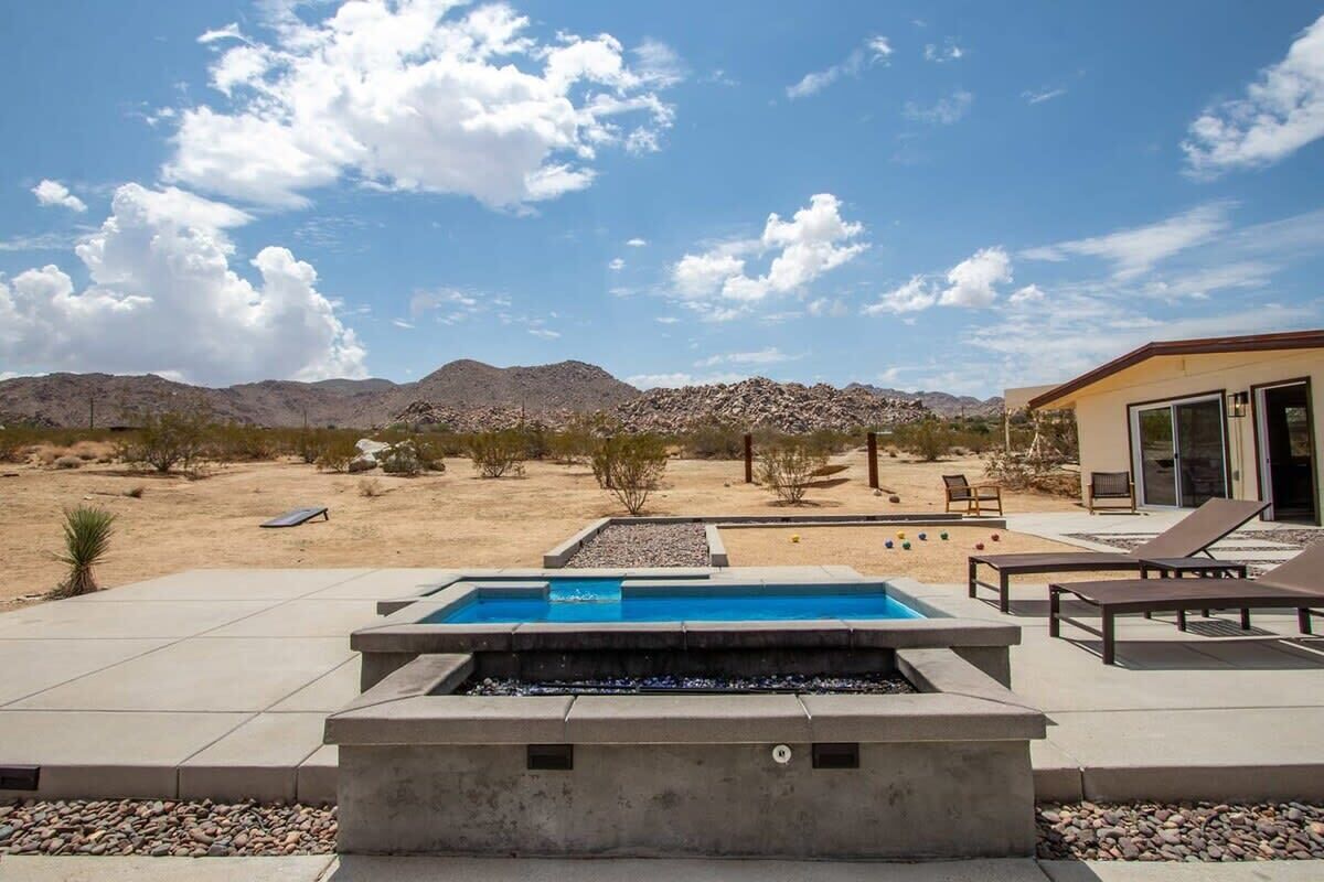 A pool area with lounge chairs, a small pool, and a desert landscape in the background.