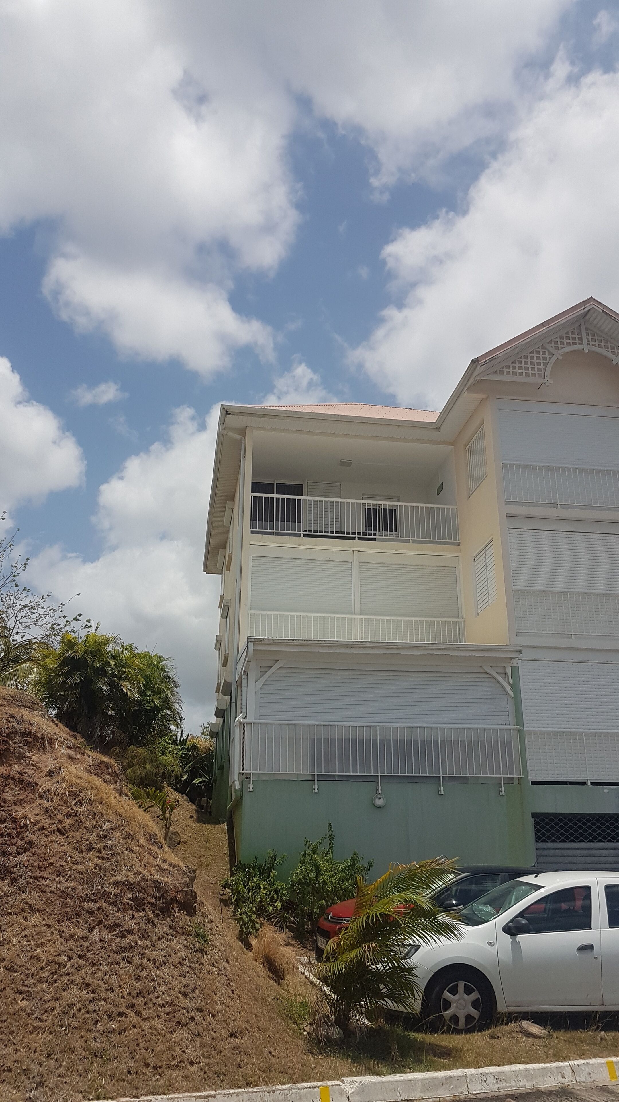 A multi-story building with balconies, a garage, and a car parked in front.