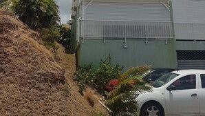 A multi-story building with balconies, a garage, and a car parked in front.