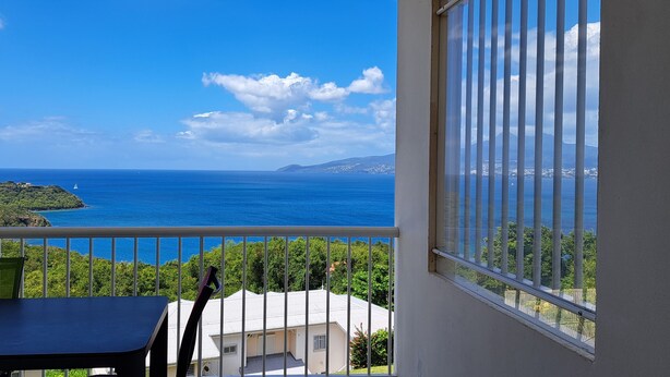 A balcony with a view of the sea and a small island.