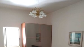 A bedroom with a bed, a wardrobe, a radiator, and a window.