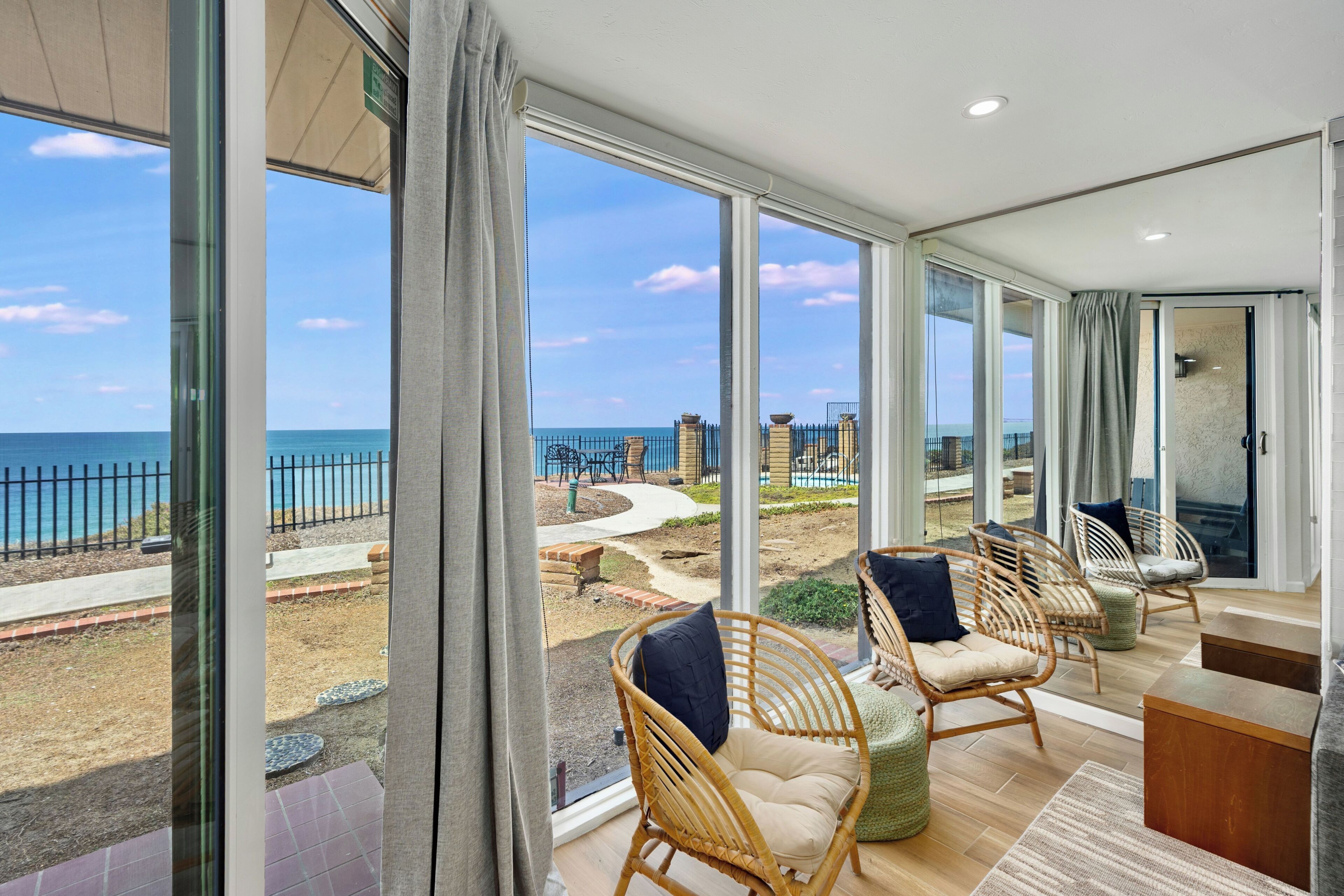 Un balcon spacieux offrant une vue dégagée sur la mer, aménagé avec des fauteuils en osier et une table en bois.