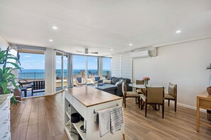 Un apartamento moderno con balcón, comedor y sala de estar con sofá y sillones.