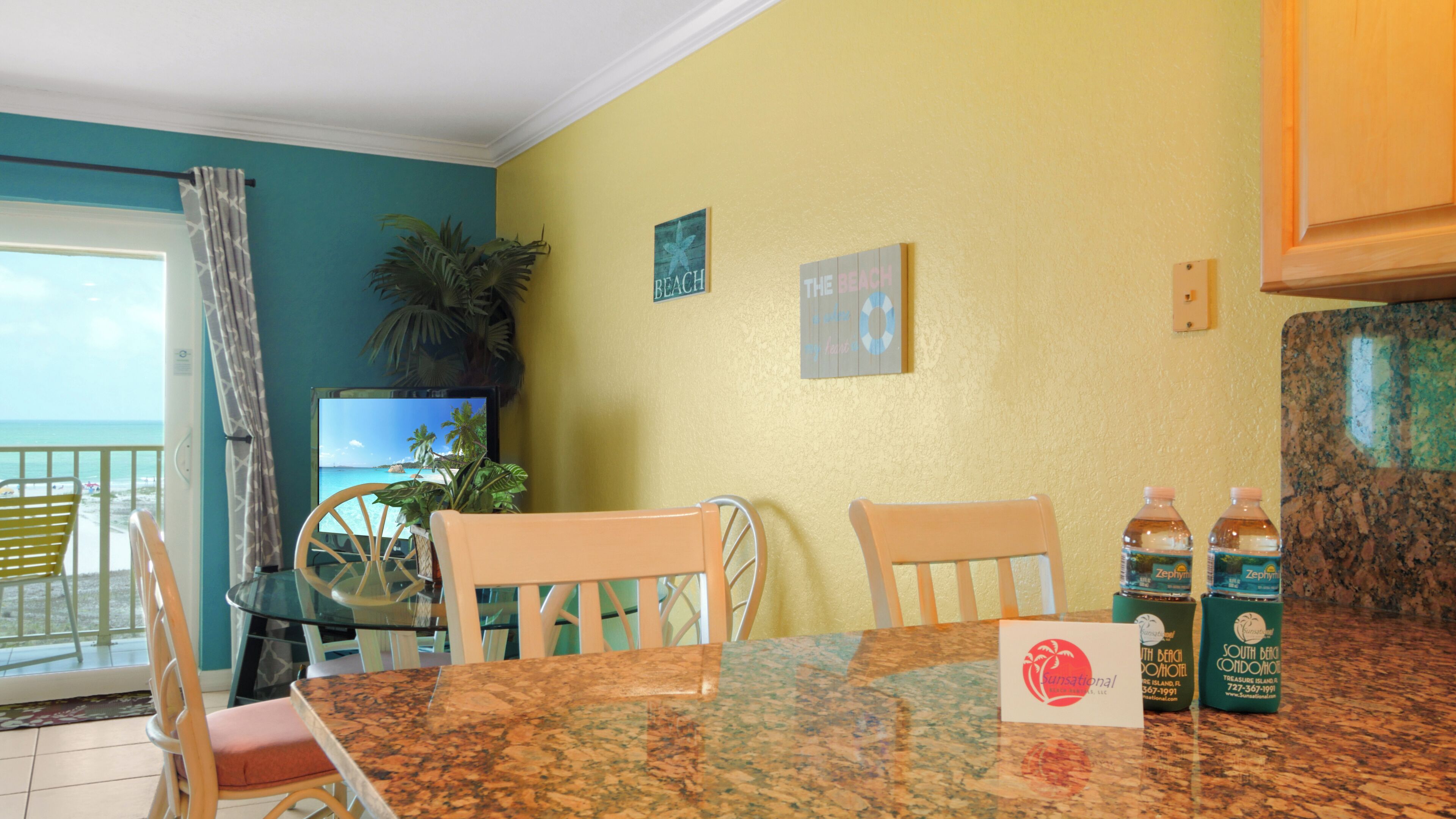 A dining area with a table, chairs, and a view of the beach.