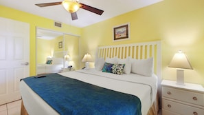 Ein Hotelzimmer mit Bett, Nachttischlampen, Deckenventilator, Nachttisch und einer Tür.
