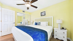 Une chambre d’hôtel avec un lit, une table de chevet, une lampe et un ventilateur de plafond.