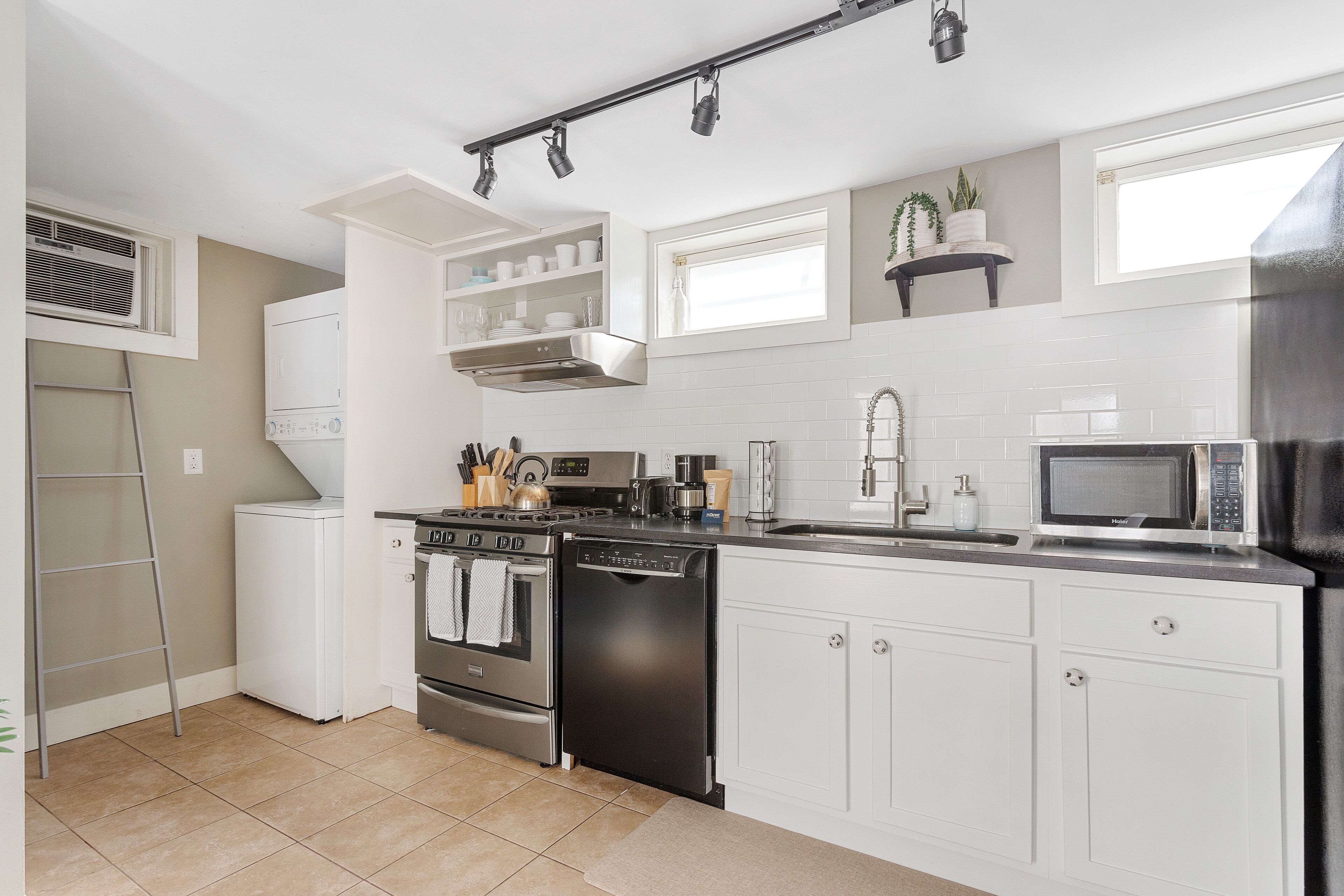 A modern kitchen with white cabinetry, stainless steel appliances, and a tiled backsplash.