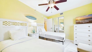 A hotel room with a bed, bedside table, lamp, dresser, and a ceiling fan. - Treasure Island Beachfront-Top Floor End Unit Stunning Sunsets South Beach 601 (Treasure Island)