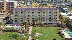 Un hotel de varios pisos con zona de piscina, rodeado de vegetación y vistas a la ciudad.