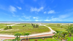 A coastal landscape with a clear sky, a beach, and a road leading to a parking area. - Treasure Island Beachfront-Top Floor End Unit Stunning Sunsets South Beach 601 (Treasure Island)